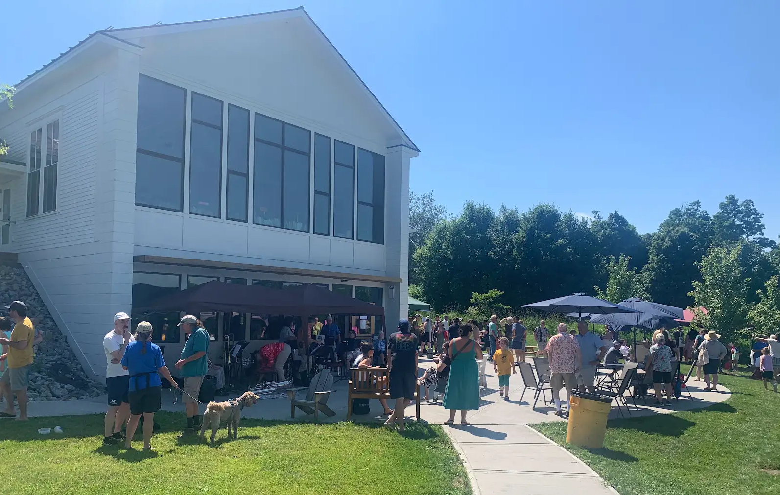 Party outside a white library building on a new walkway with umbrellas.