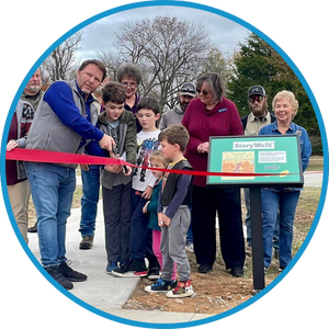 They partnered with the City of Gravette Parks Department and the Gravette Police Department to install a StoryWalk at a local park. The photo is of the ribbon cutting.